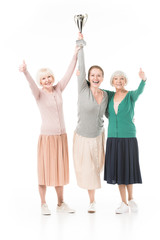 Obraz premium Three smiling stylish women celebrating with trophy cup isolated on white