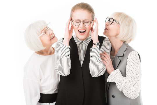 Mature stylish businesswoman shutting ears between two senior businesswomen in eyeglasses isolated on white
