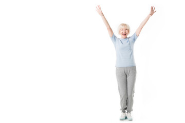 Happy senior sportswoman standing with arms up isolated on white