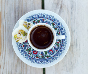 Top view cup hot black Turkish coffee and traditional sweets.