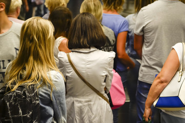 People wait in line seen from behind. Blurry