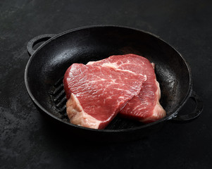 Fresh raw beef meat steaks in the black plate on black  background