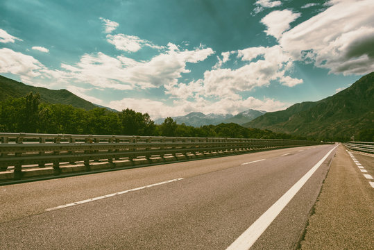 Motorway road in Alps, beautiful day time landscape with blue sky and clouds. Vintage style image