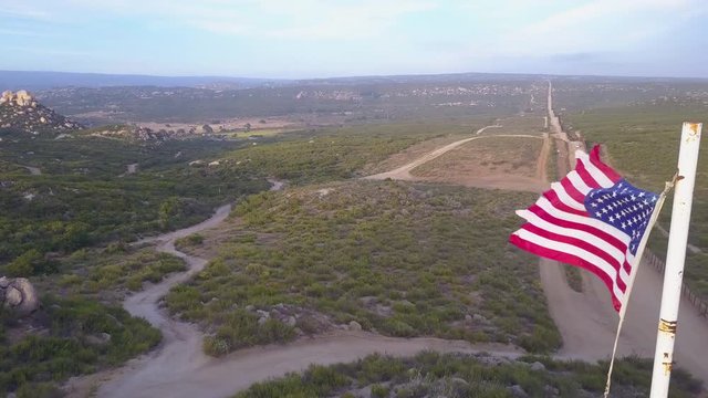 The American flag flies over the U.S. Mexico border wall in the California desert.