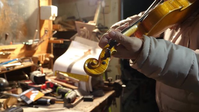 Luthier play violin in his workshop