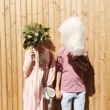 Bride and groom holding cotton candy and flowers in front of their faces