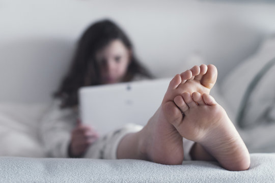 Teenage Girl sitting on her bed using a computer