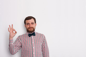 Fototapeta premium Young bearded caucasian man hipster show ok gesture in studio with white background