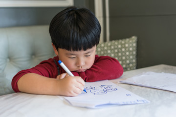 A Asian boy is drawing a picture.