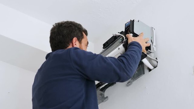 technician assembling the air conditioner to the wall