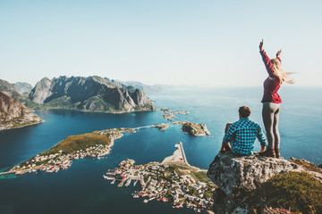 Couple travelers traveling together on top cliff Reinebringen mountain in Norway man and woman...