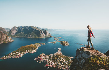 Fototapeta na wymiar Woman traveler standing alone on cliff edge in Norway lifestyle exploring concept adventure outdoor summer vacations Lofoten islands Reinebringen mountain top