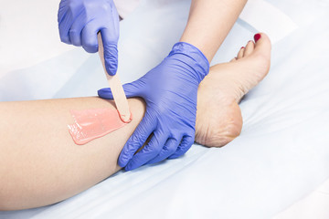 The process of classical wax depilation of female limbs in the beauty salon. 