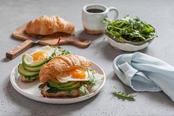 Breakfast with Croissant sandwiches with Fried Egg, Salad Leaves and avocado