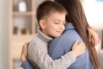 Woman hugging little boy indoors. Child adoption