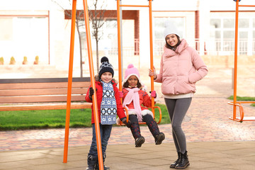 Young woman with little kids on playground. Child adoption