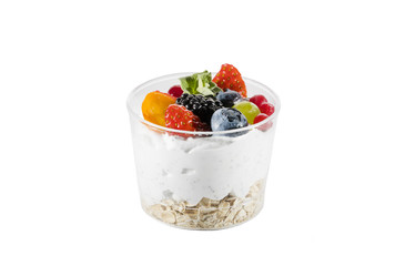 Creamy cream dessert in a plastic cup decorated with berries on a white background. 