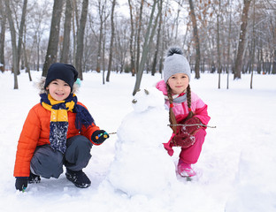 Fototapeta na wymiar Happy children making snowman in park on winter vacation