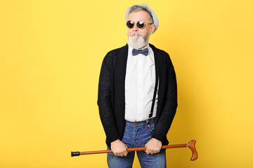 Happy senior man in hipster outfit on color background