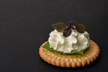 Biscuit cracker appetizer with cream cheese and basil topping