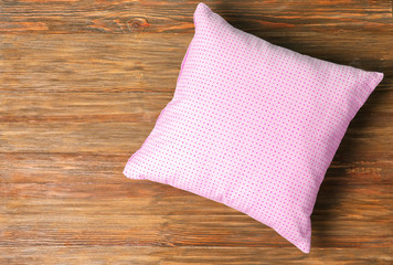 Soft decorative pillow on wooden background