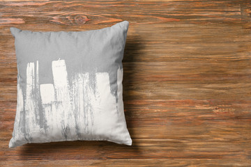 Soft decorative pillow on wooden background