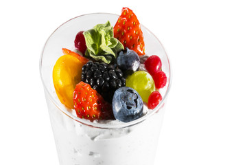 Creamy cream dessert in a plastic cup decorated with berries on a white background. 