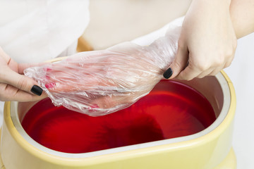 Process paraffin treatment of female hands in beauty salon .