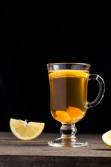 A cup of ginger tea with lemon on a wooden background.