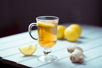 A cup of ginger tea with lemon on a wooden background.