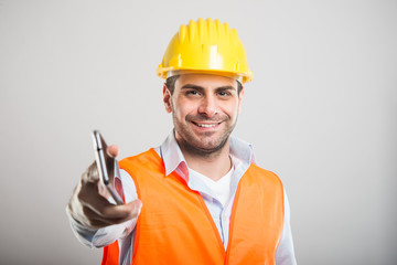 Portrait of young architect handing telephone