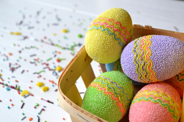 Colorful easter eggs with flowers and yellow candle in the basket. Beautiful easter background. Easter card. Homemade holiday decor.