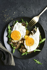 Whole grain toasts with sauteed mushrooms, fried eggs and arugula leaves.Top view with copy space.