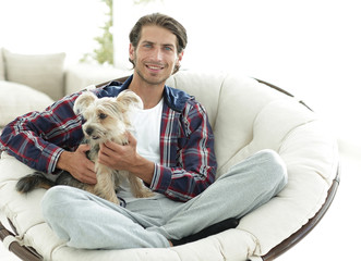 handsome guy with a dog sitting in a large armchair.