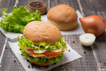ready burger in the foreground, a few buns and spices on old boards