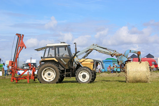 Front loader grabbing a hay bale