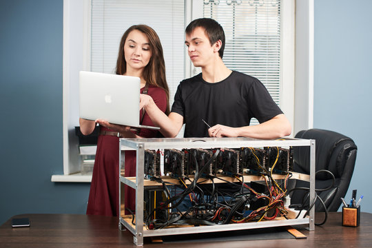 Young man and woman setting up video card farm for cryptocurrency mining