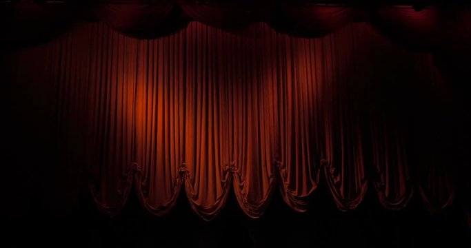 A closed red stage curtain in a theater

