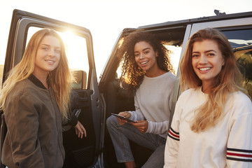 Three female friends on a road trip using a tablet, close up