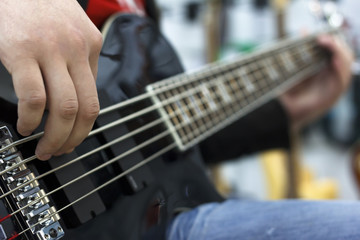 Obraz premium close up on the fingers of musician playing bass guitar on the stage