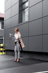 businesswoman talking on smartphone while reading newspaper on street