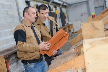 workmen in discussion holding roof tile