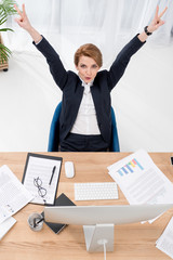 overhead view of businesswoman showing peace sign at workplace in office