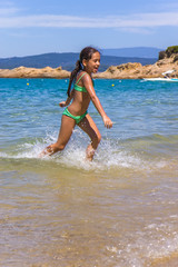 Girl running and splashing on the shallow beach