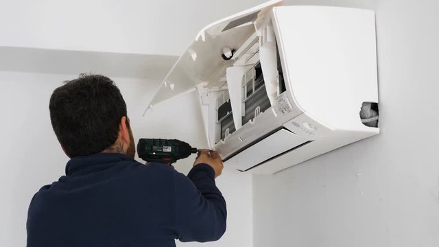 technician uses the drill by mounting the air conditioner to the wall