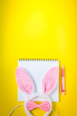 Easter holiday background with notebook, pen and bunny ears