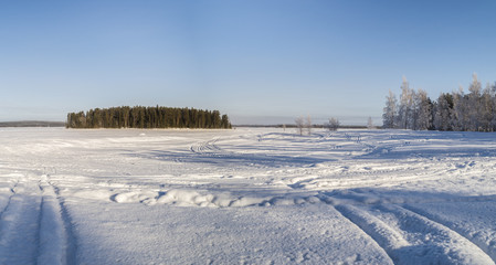 Fototapeta na wymiar An island in frozen snow covered lake 