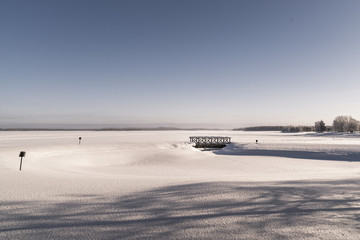 Winter landscape. Small bridge on snow covered lake.