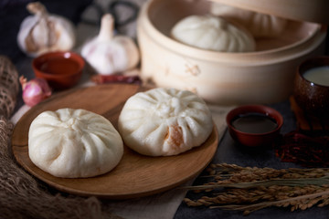 Chinese breakfast: Steamed buns (Baozi) on wooden plate, with ba