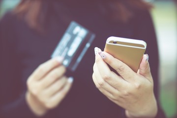 female hands holding credit card and using phone. Online shopping purchase Sell or Payment. filler vintage.